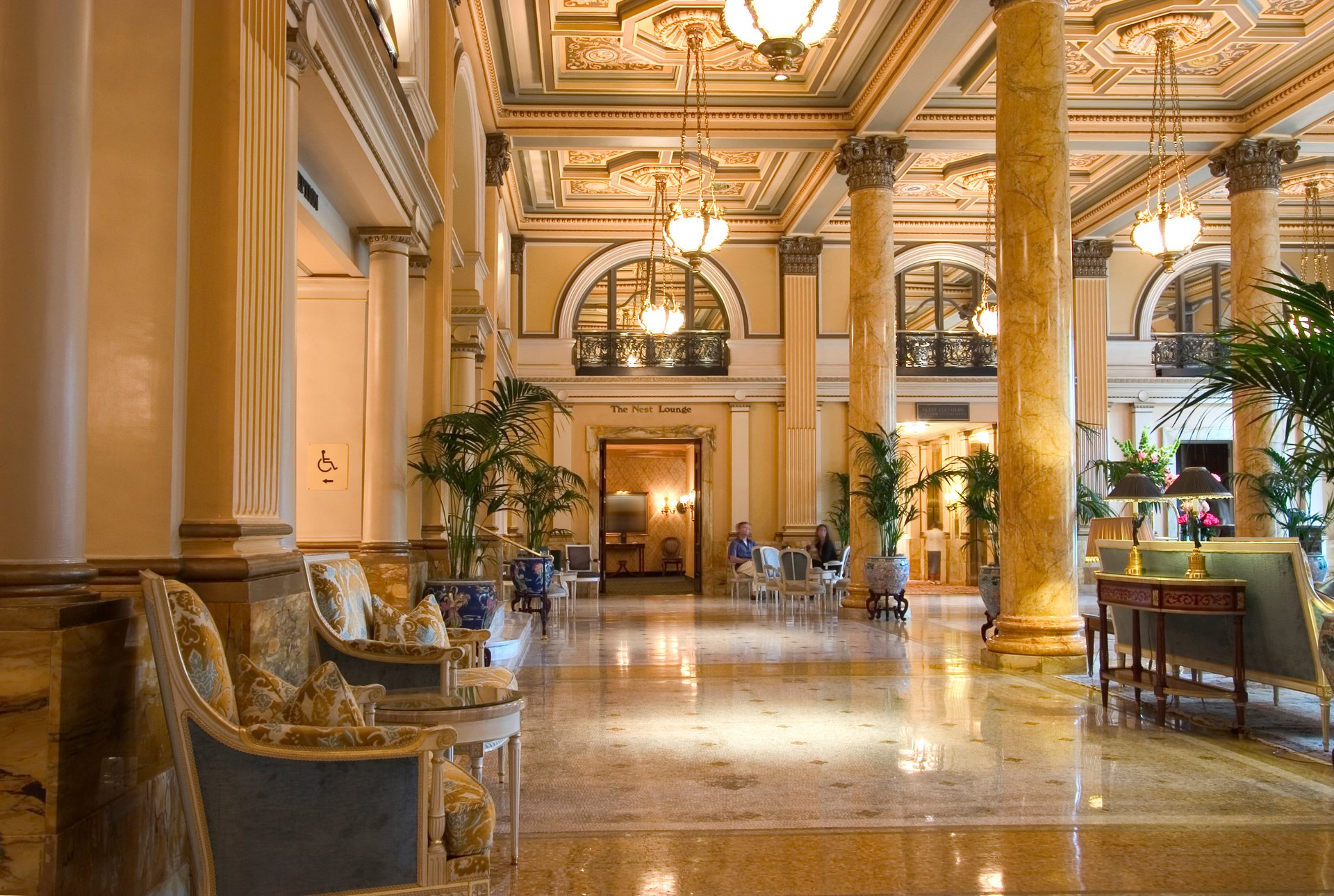 Grand classical hotel lobby with marble columns, ornate ceiling, chandeliers and seating